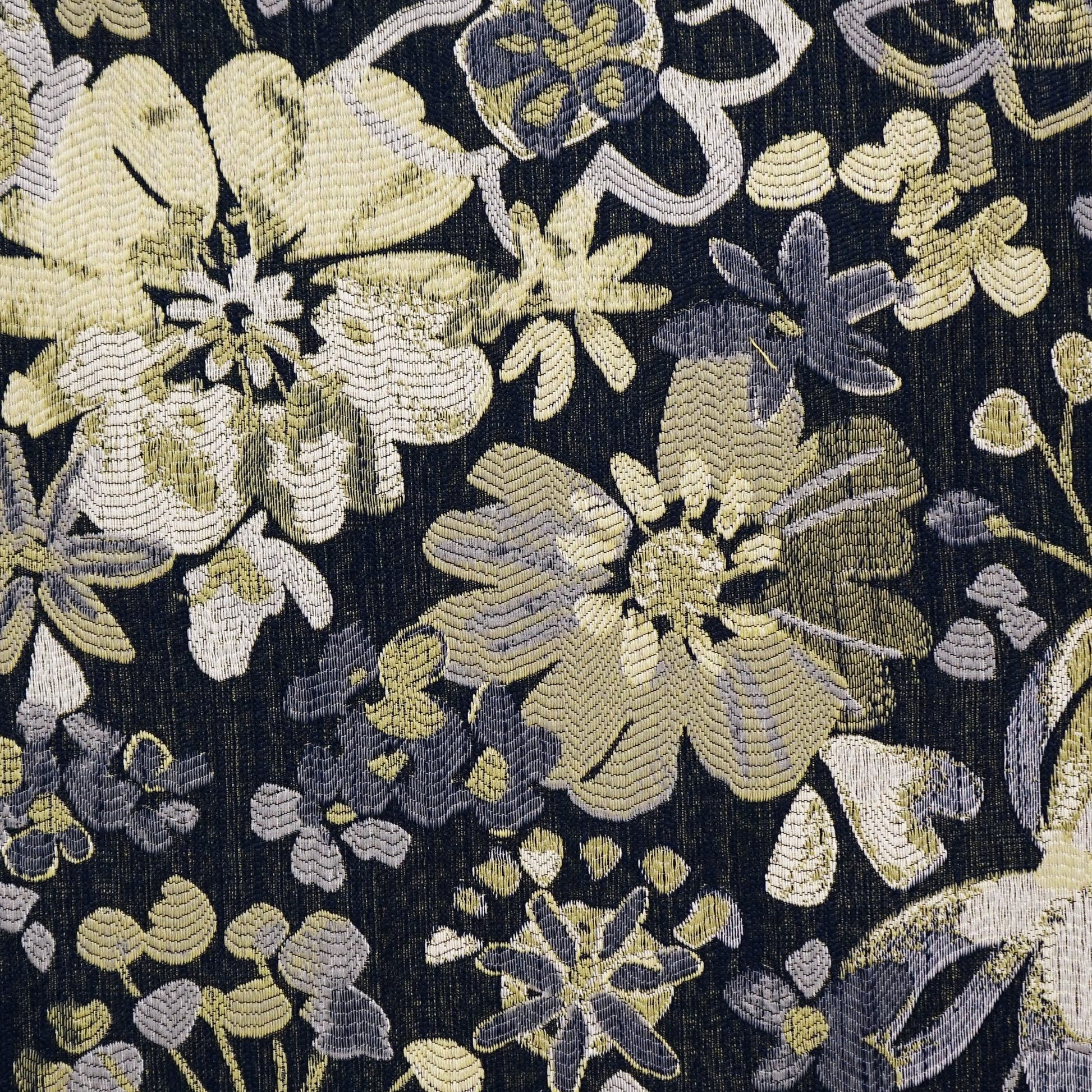 Dark jacquard fabric featuring a large green floral pattern on a black background.
