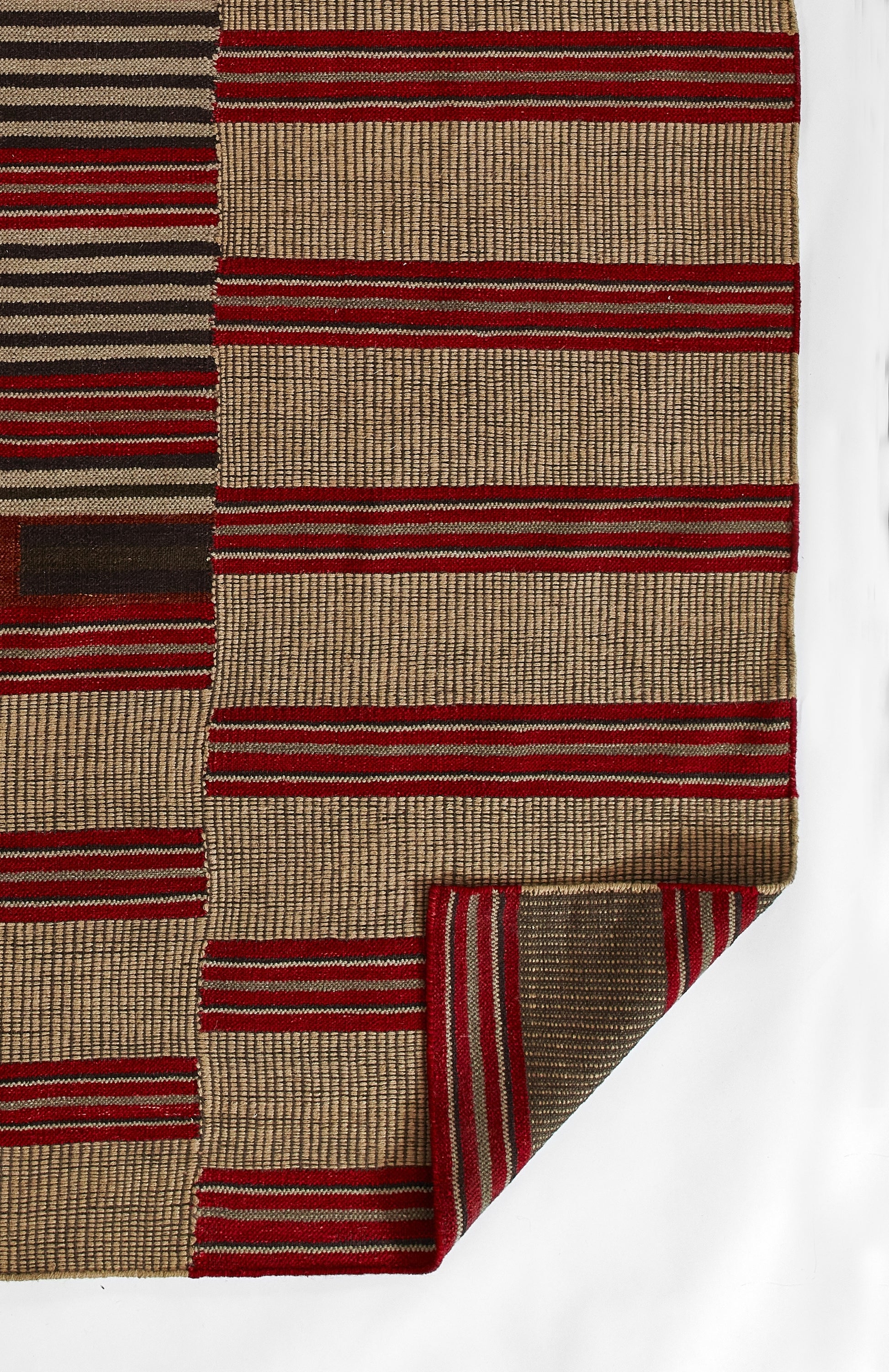 Handwoven wool rug with red and tan striped blocks in a geometric pattern; folded corner.