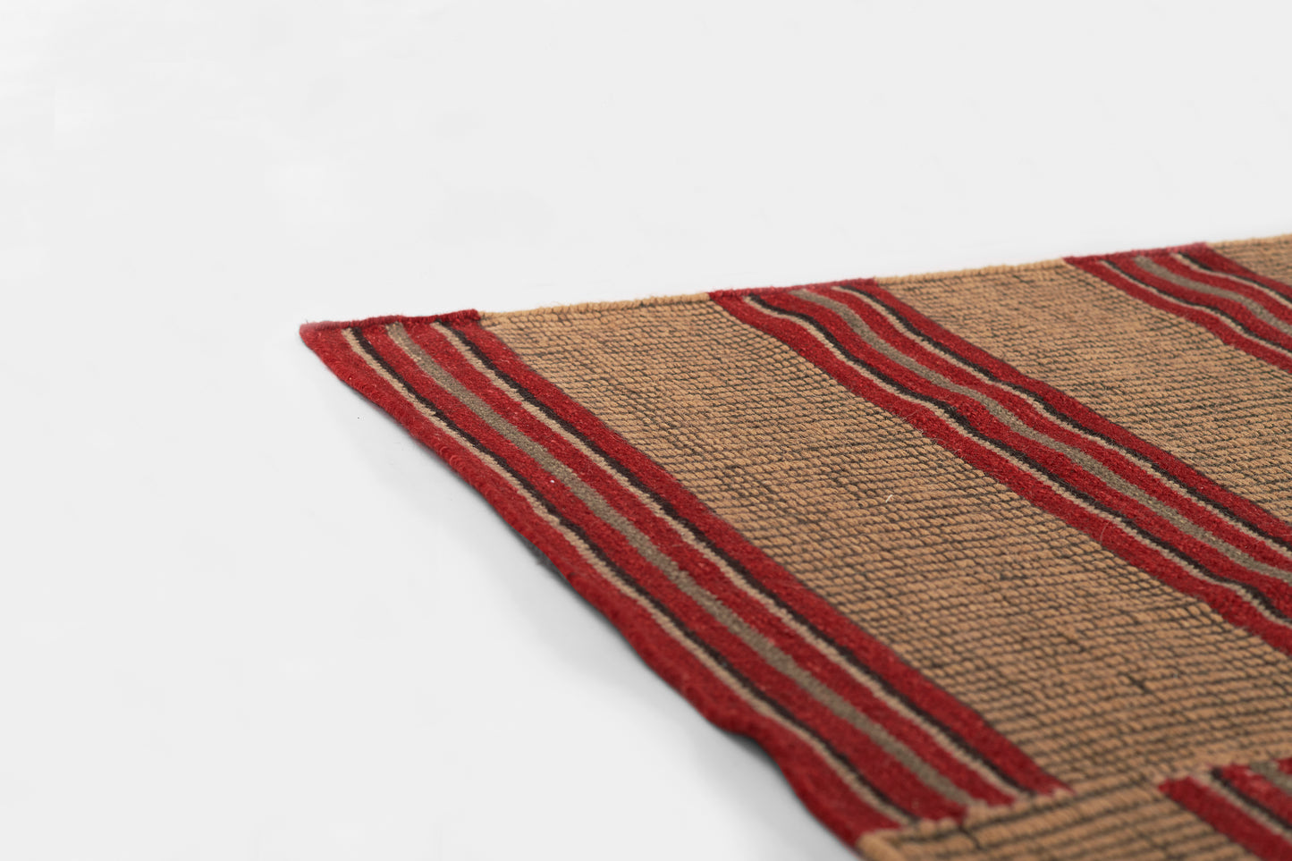Beige flat-weave jute rug with red striped border, corner view.
