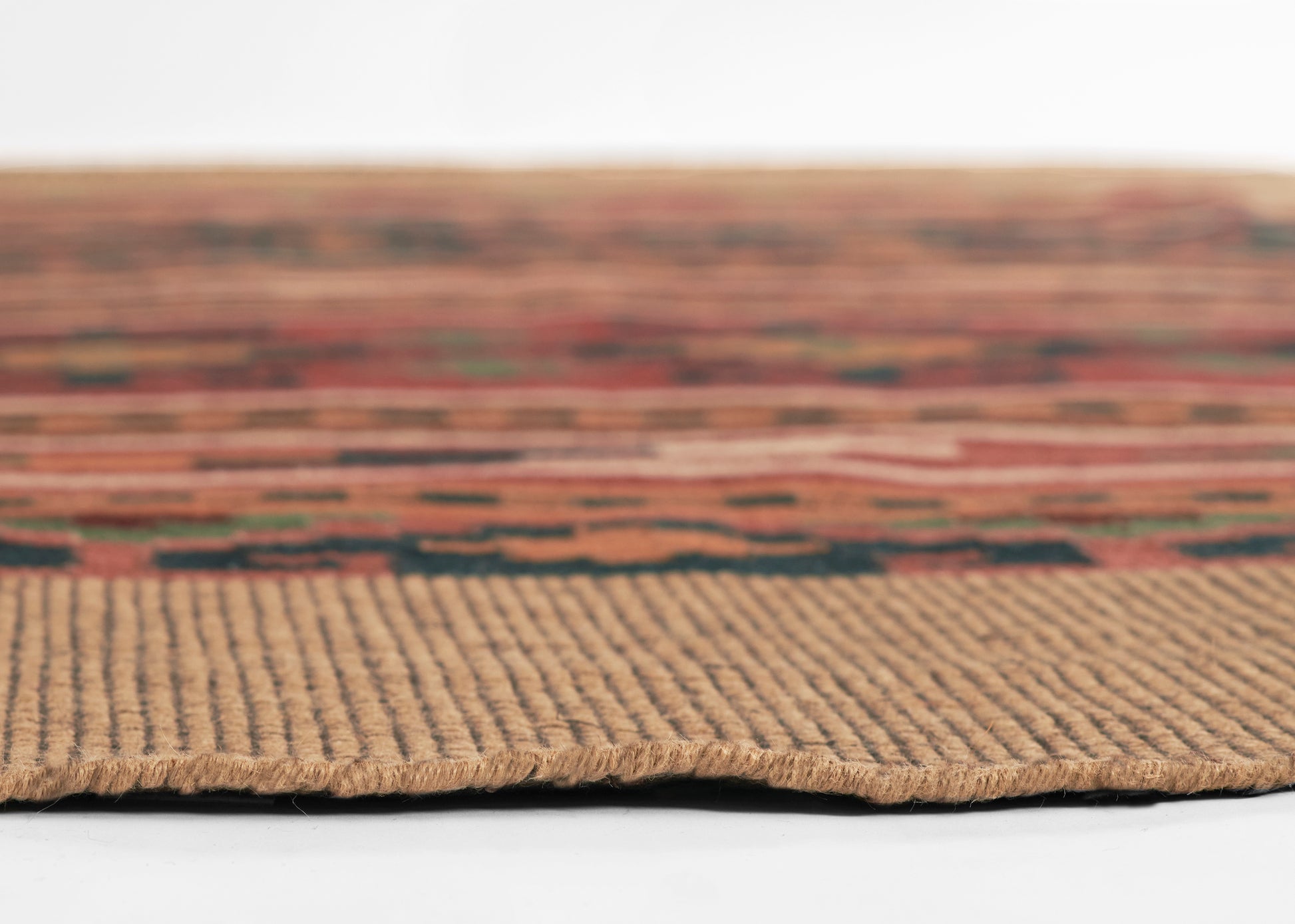 Close-up of a multicolor kilim-pattern rug with a beige woven border and earthy tones.