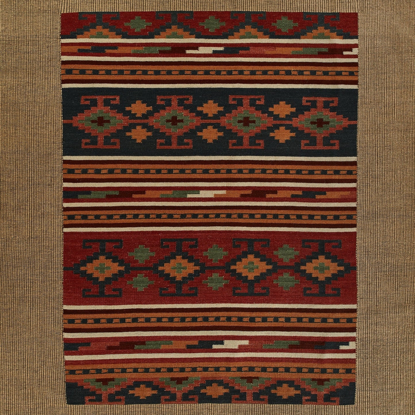 Rectangular kilim-style wool rug featuring bold geometric tribal motifs in red, navy, orange, green, cream.