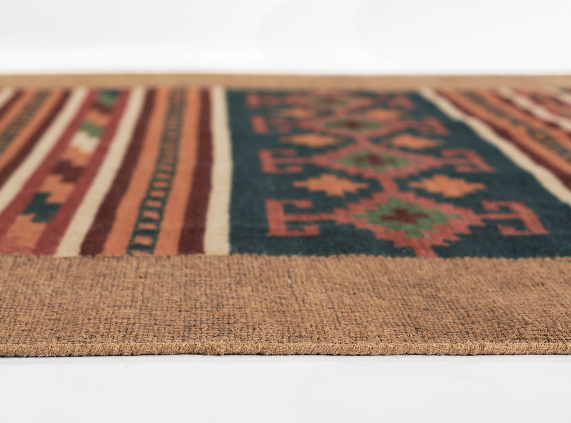 Close-up of a woven tribal kilim rug runner: tan border, navy field with red geometric motifs and striped edges