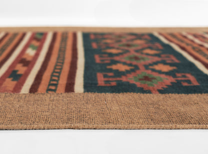Flat-woven kilim-style rug with geometric tribal motifs in navy, orange, red and cream; natural jute border.
