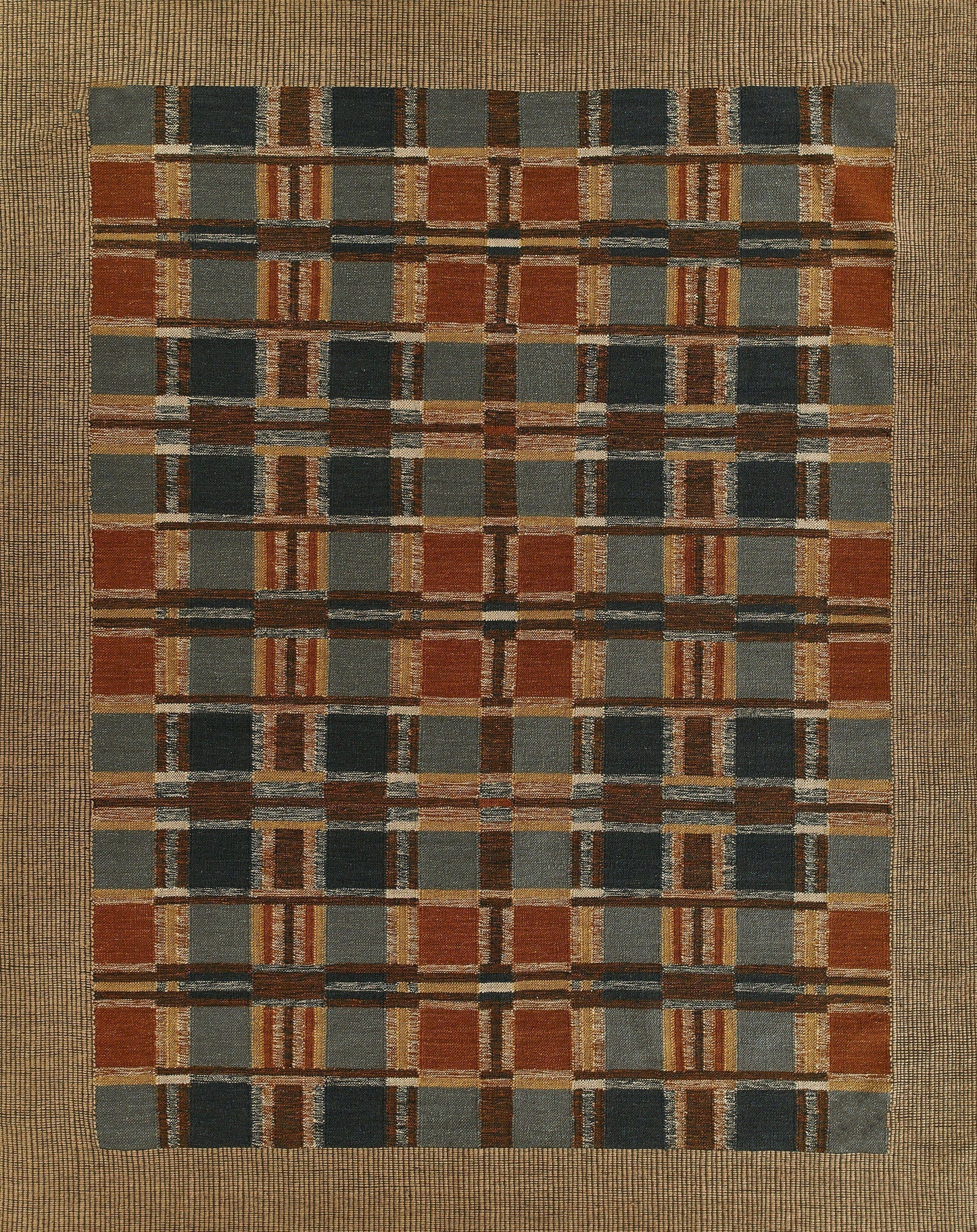 Woven rectangular rug with plaid grid in rust, navy, charcoal, tan and blue-gray; earthy tones.