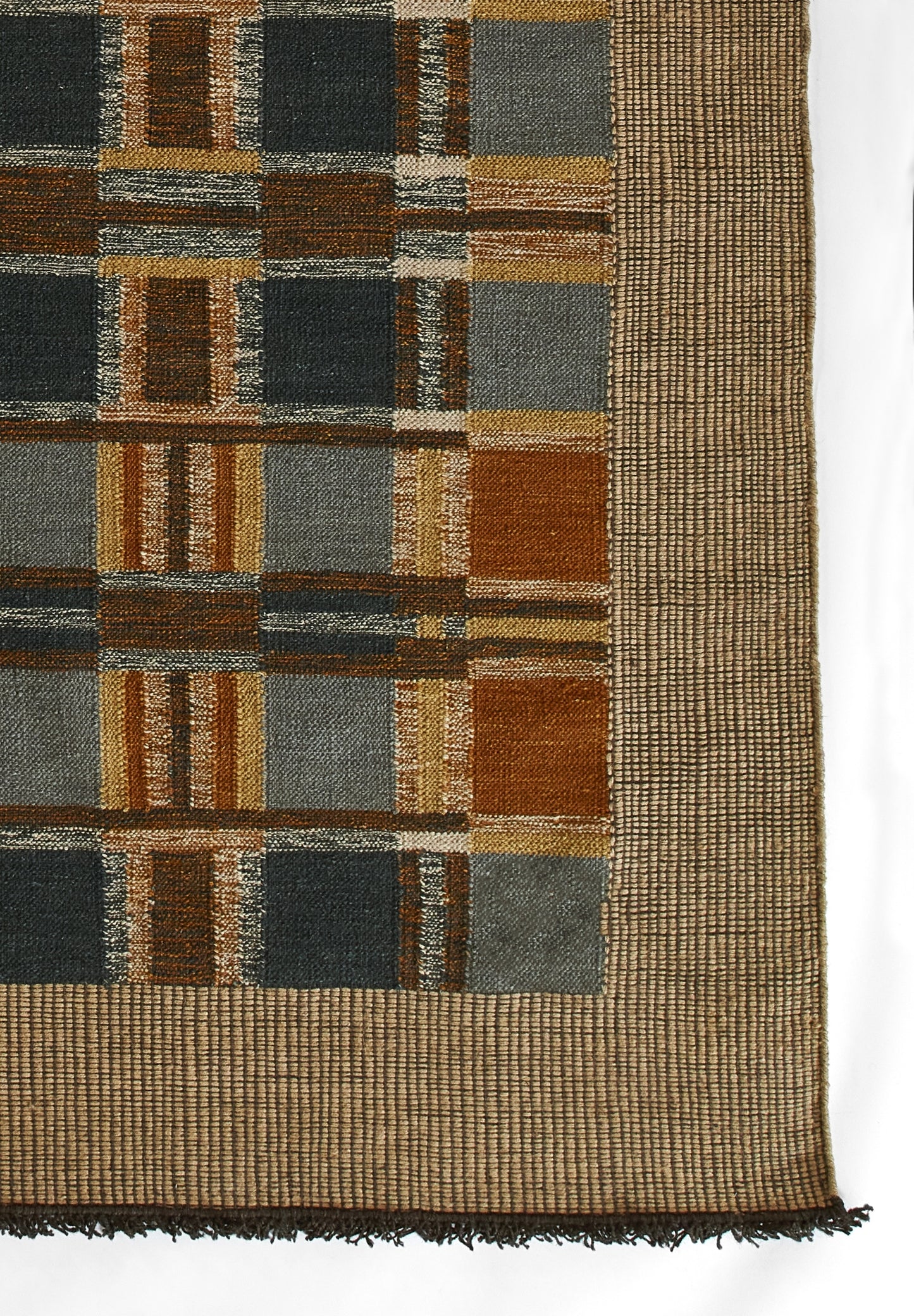 Rectangular woven rug with earthy brown, slate blue and gray blocks in a grid, framed by a tan border and fringe.