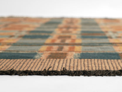 Close-up of a woven plaid rug in orange and teal blocks with fringed edge, cozy home decor.