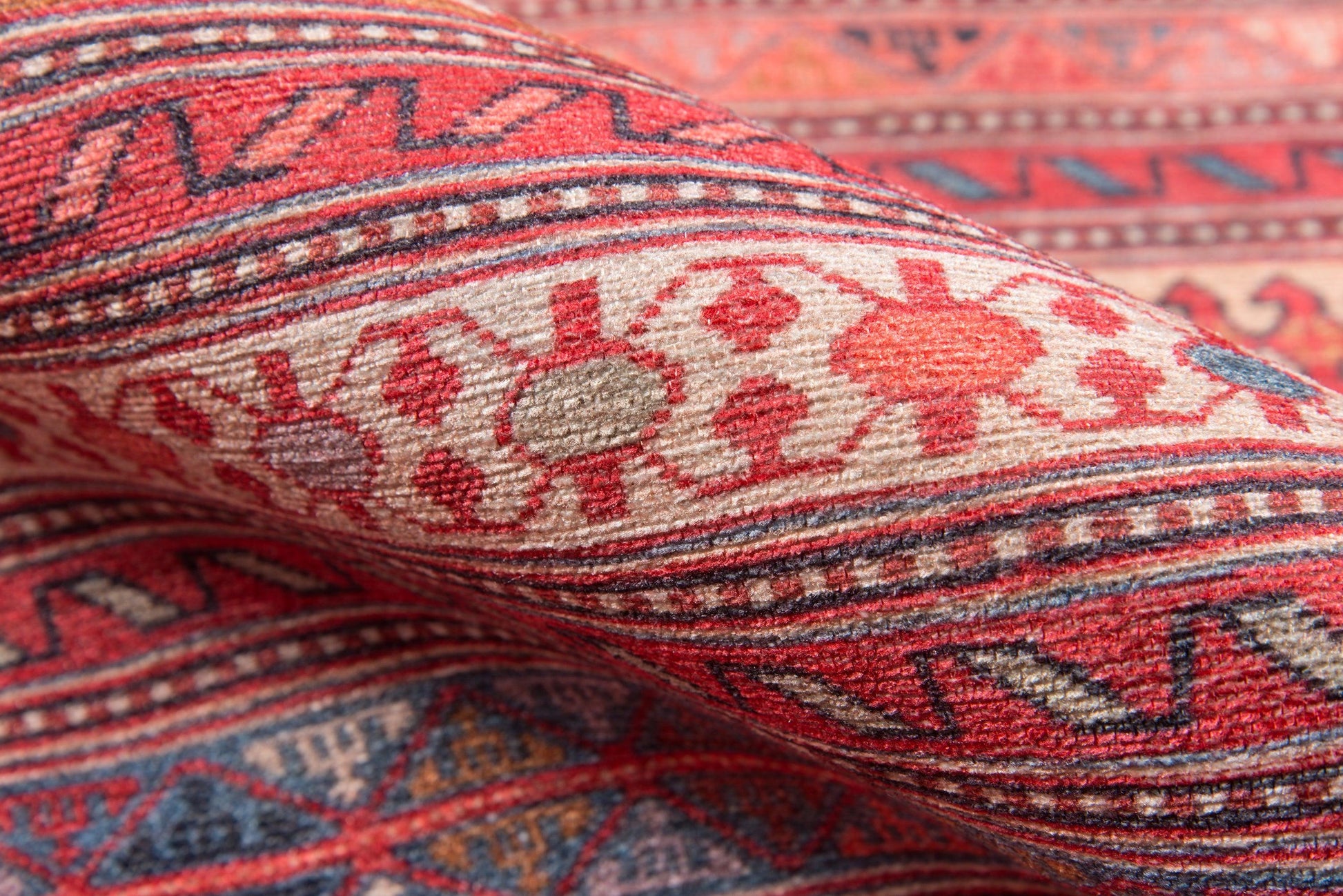 Close-up of a wool kilim-style rug with red, cream and blue geometric tribal motifs.