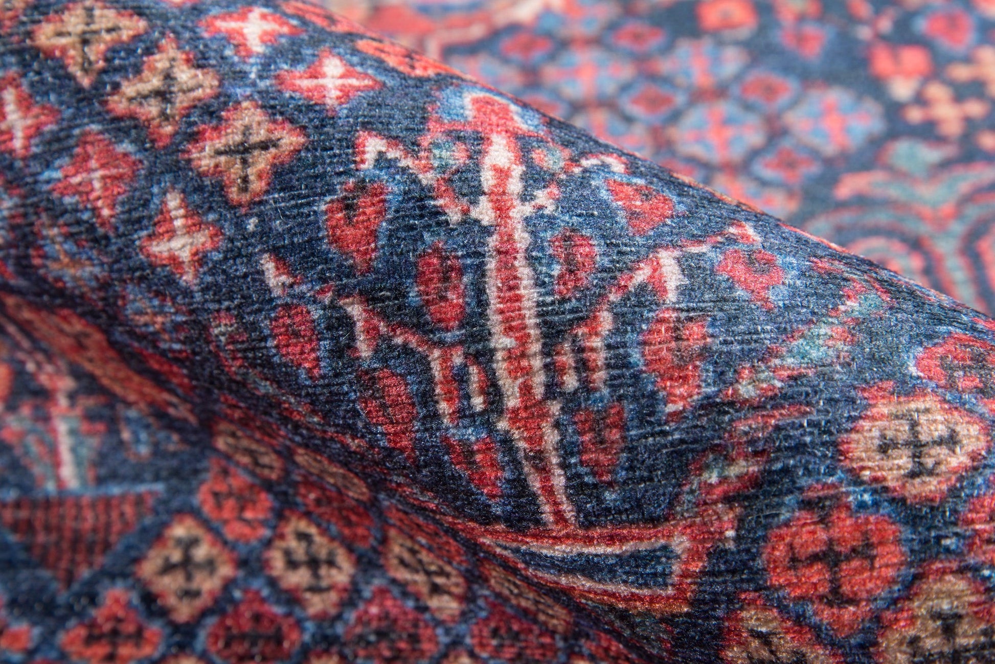 Close-up of a navy blue oriental rug with red and ivory geometric motifs and woven texture.