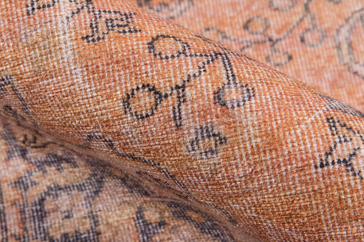 Orange-tan woven rug with blue-gray geometric floral motifs; textured, cozy home decor.