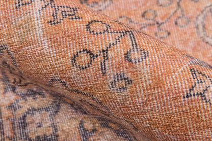 Orange-tan woven rug with blue-gray geometric floral motifs; textured, cozy home decor.