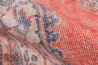 Close-up of red, cream and blue woven rug with geometric oriental pattern and folded edge.