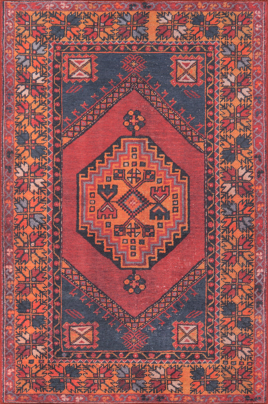 Afghan-style rectangular wool rug with red central diamond medallion, navy field, orange border and geometric motifs.