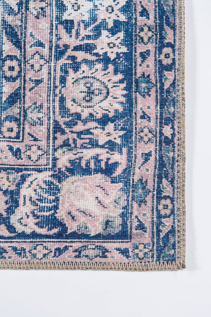 Pink and navy blue oriental rug corner with floral medallions, decorative border and beige fringe.