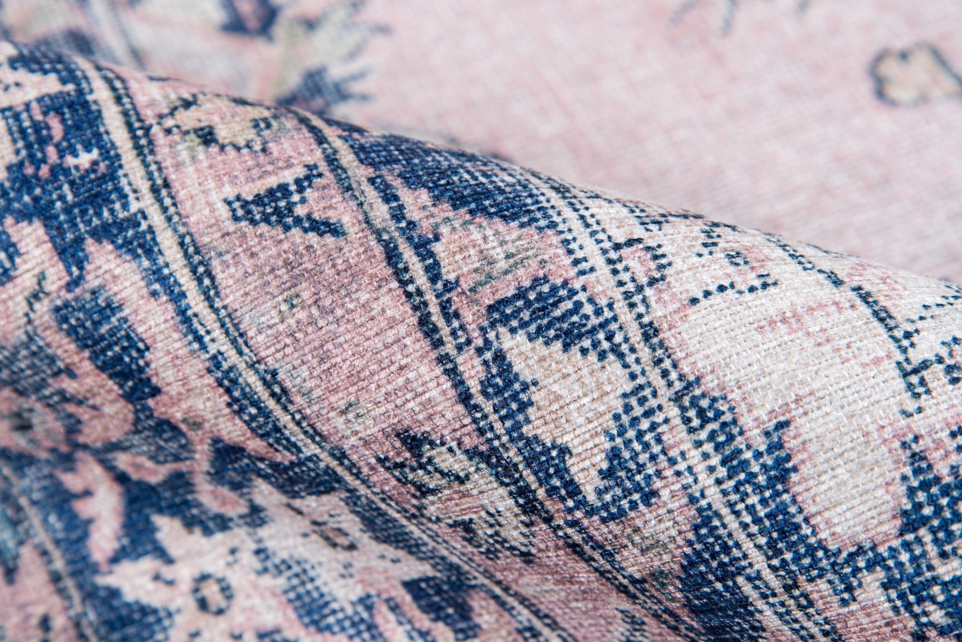Close-up of pink and navy oriental rug fabric with floral motifs and woven texture.