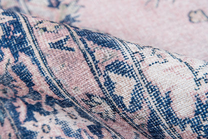 Close-up of pink and navy oriental rug fabric with floral motifs and woven texture.