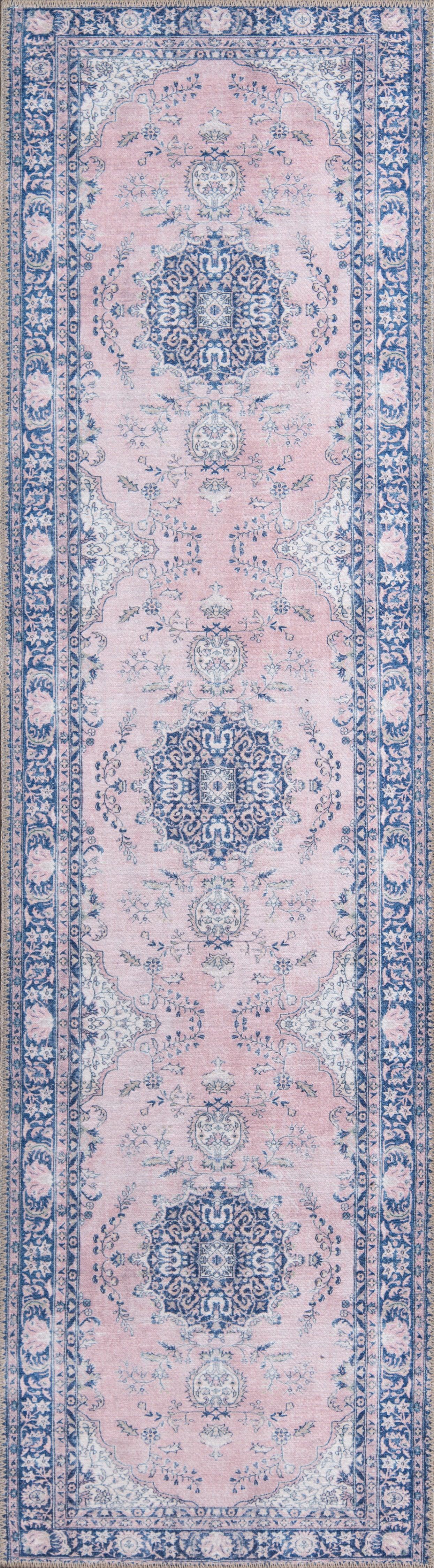 Pink field oriental rug with large navy blue medallions, pale blue florals, and an ornate blue border.