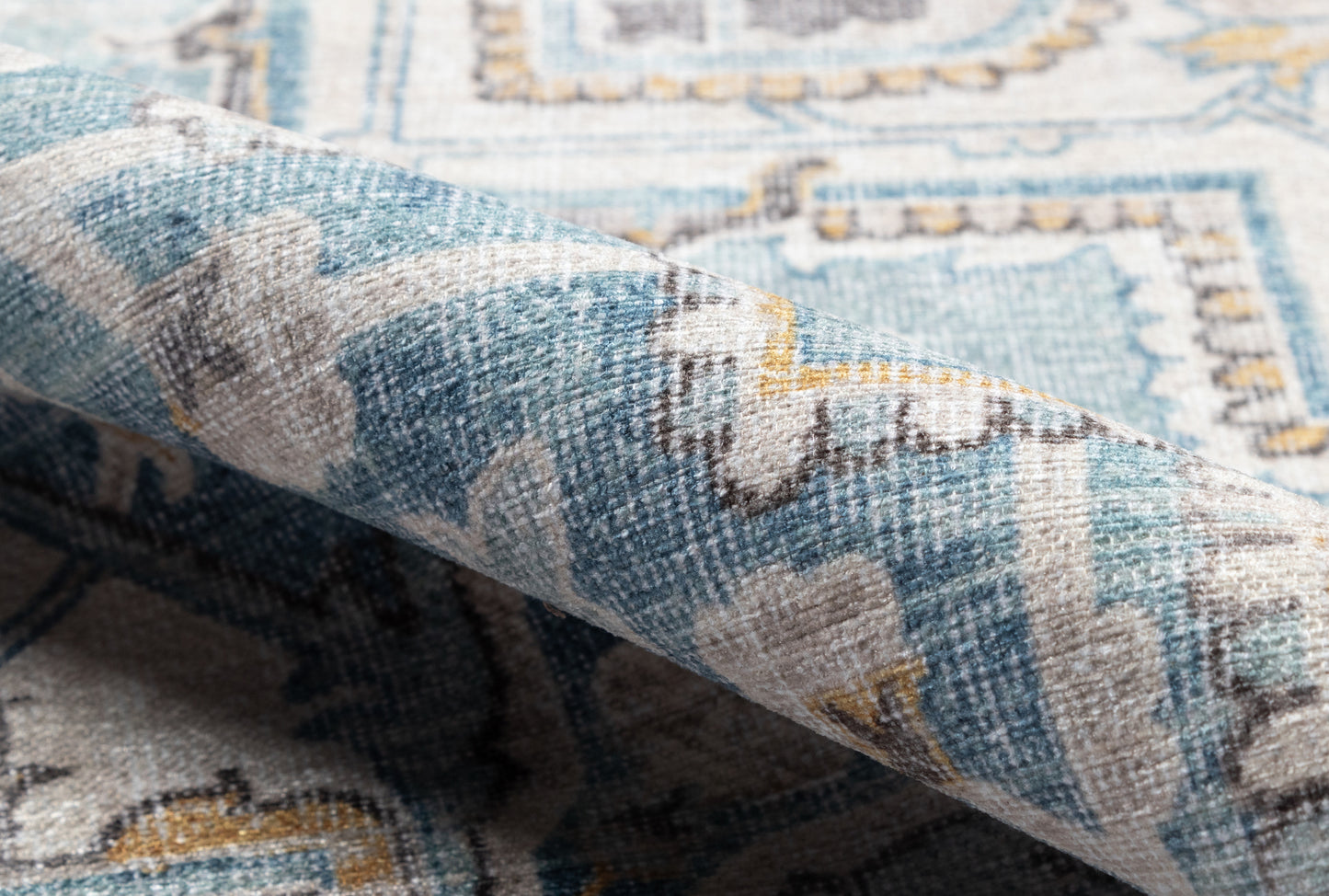 Blue teal and beige geometric rug with textured weave and folded corner.