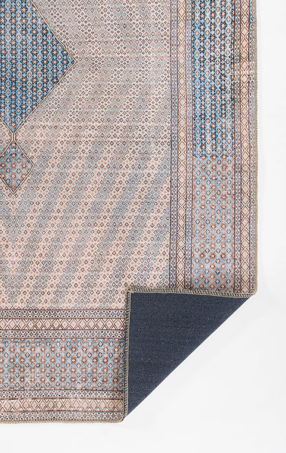 Beige Persian-inspired rug with blue geometric border and small repeating motifs; folded corner reveals navy reverse.