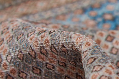 Close-up of leopard-print woven rug in brown, tan and blue tones, softly folded as a rug runner.