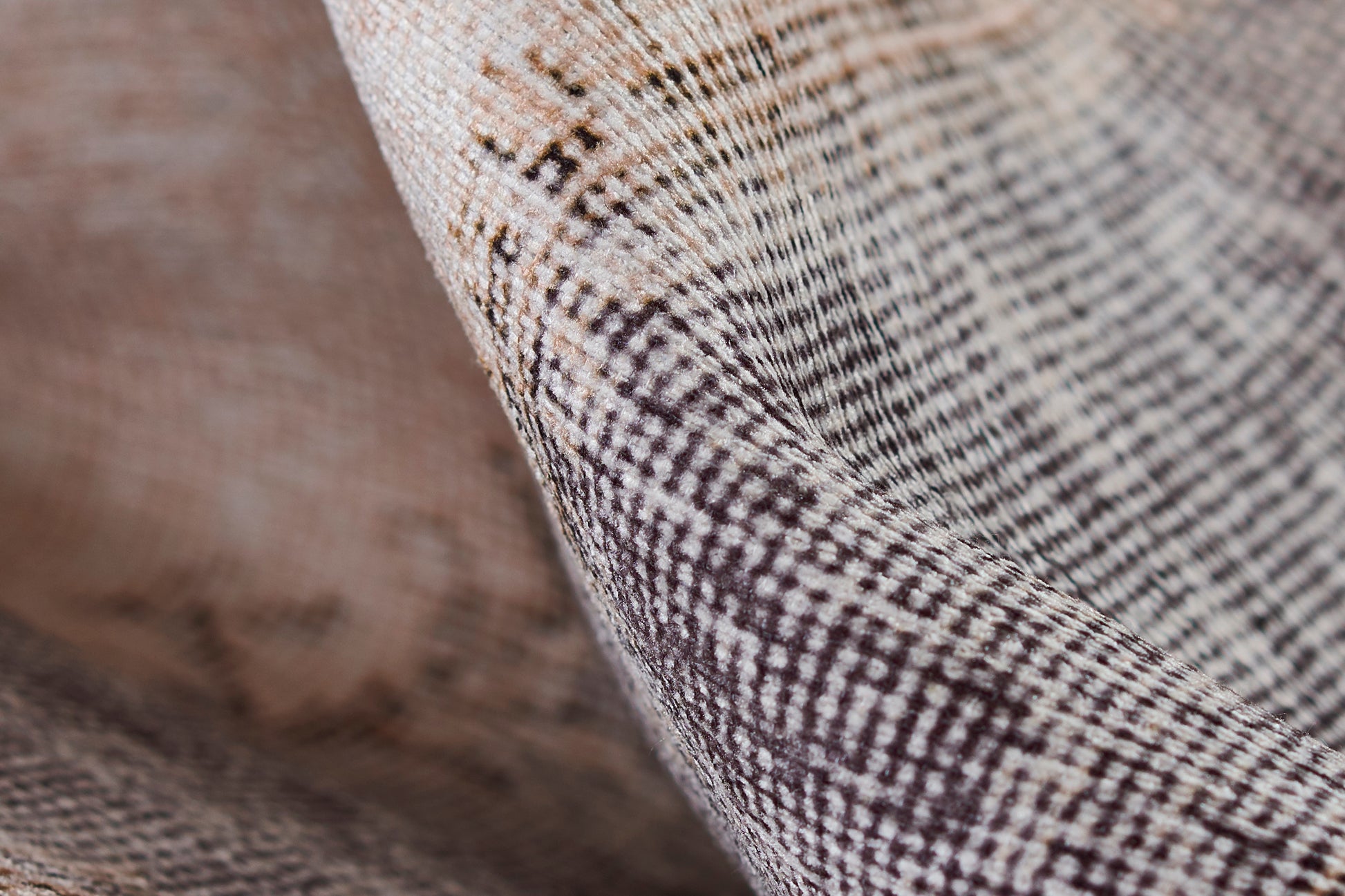 Close-up of brown & cream checkered woven rug with textured tweed-like fibers.