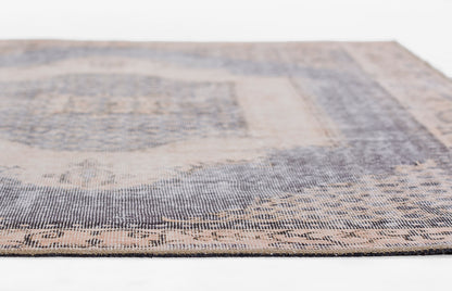 Close-up of a blue and beige woven rug with a distressed pattern and decorative border.
