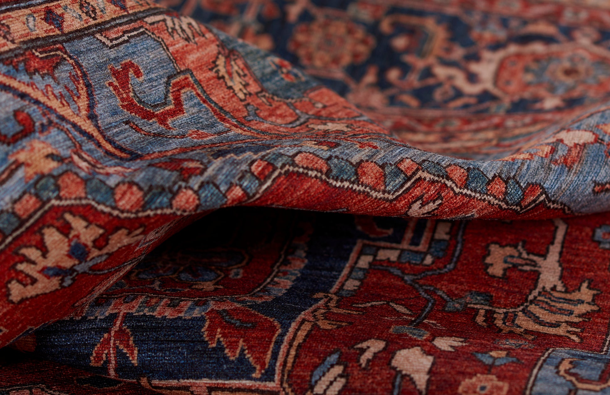 Folded red and blue Persian-style rug with floral motifs and woven texture.