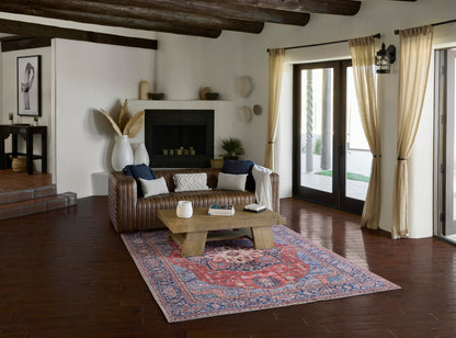 Rustic living room with a brown leather sofa, white cushions, solid wood coffee table on a red runner rug & exposed beams.