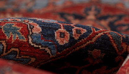 Close-up of a woven rug with red, blue and ivory geometric motifs and rich texture.