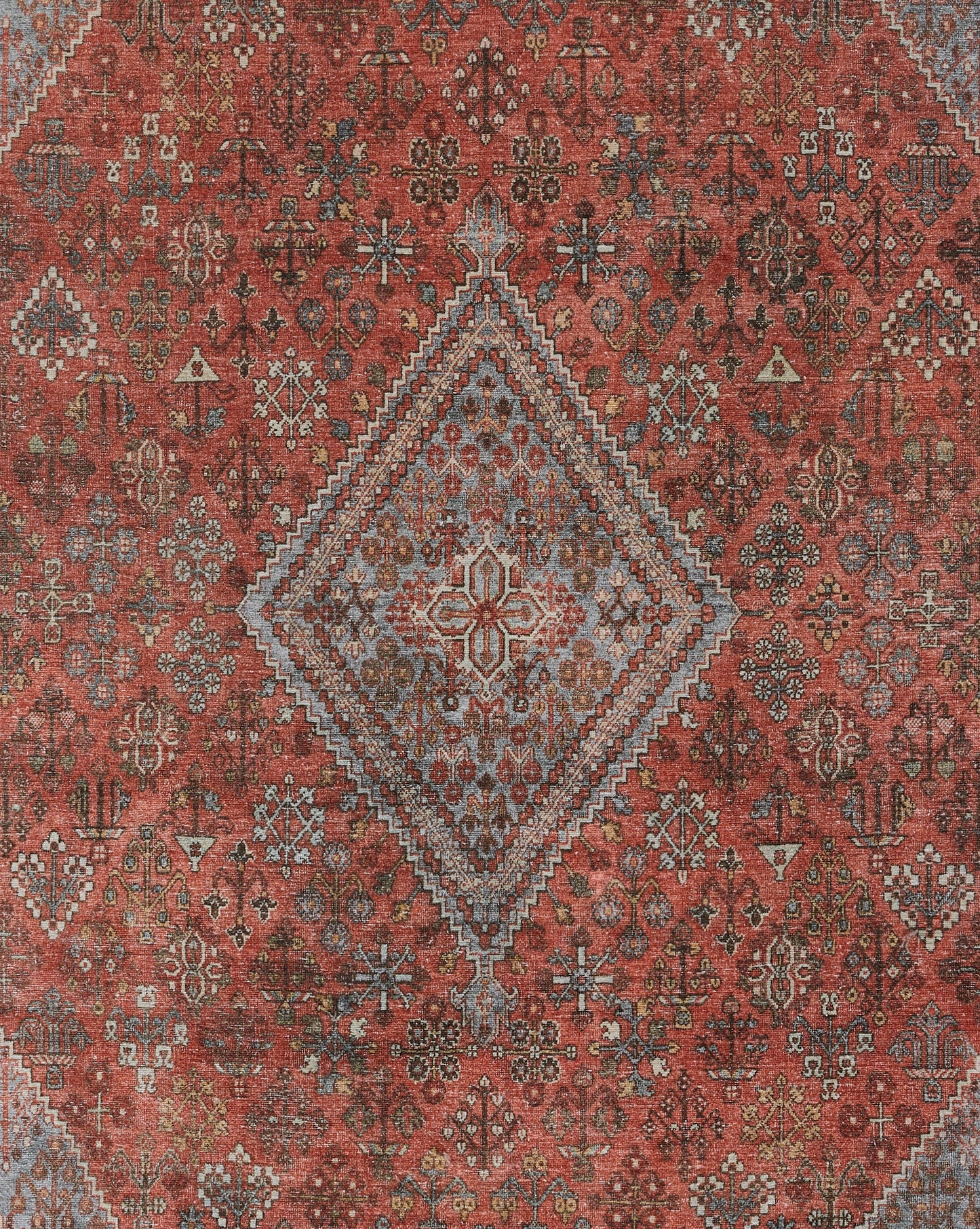 Rust-red oriental rug with a blue-gray diamond medallion, intricate floral-geometric motifs and a warm distressed look.