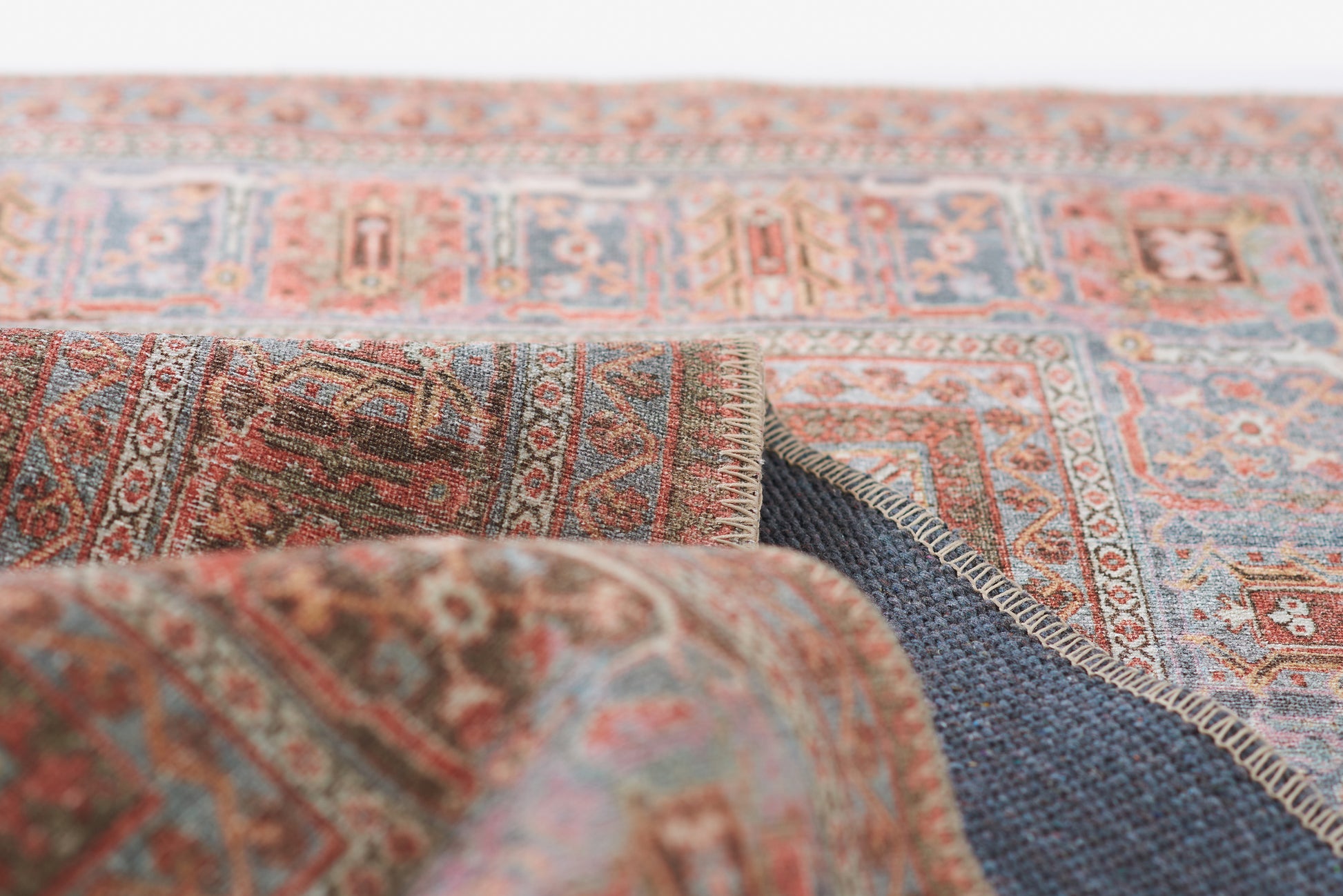 Close-up of a traditional Persian rug in blue, red and beige hues, woven wool with a fringed edge.