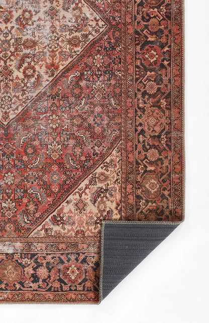 Persian-style oriental rug with red, ivory and black floral pattern; intricate border, folded corner showing navy reverse.