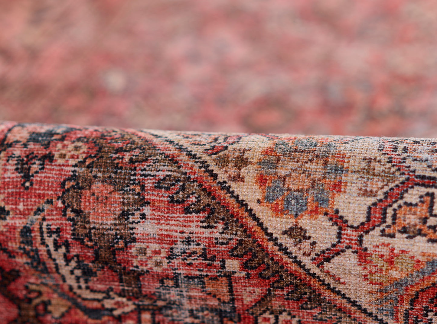 Close-up of a red oriental rug with intricate floral motifs, featuring beige, orange and blue accents.