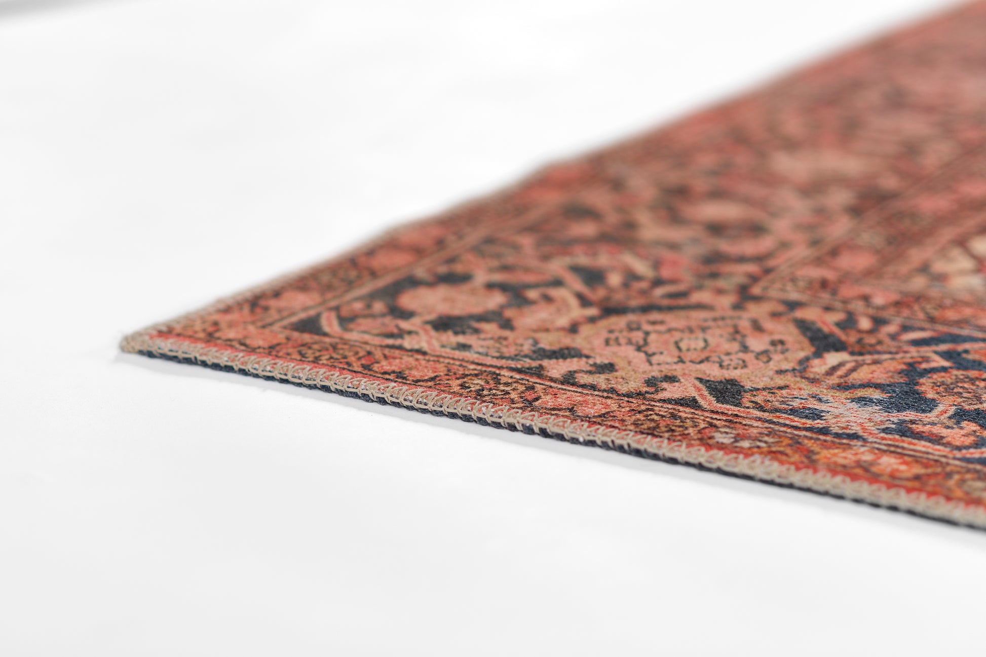 Close-up of a red Persian-style rug corner with navy and ivory floral patterns.