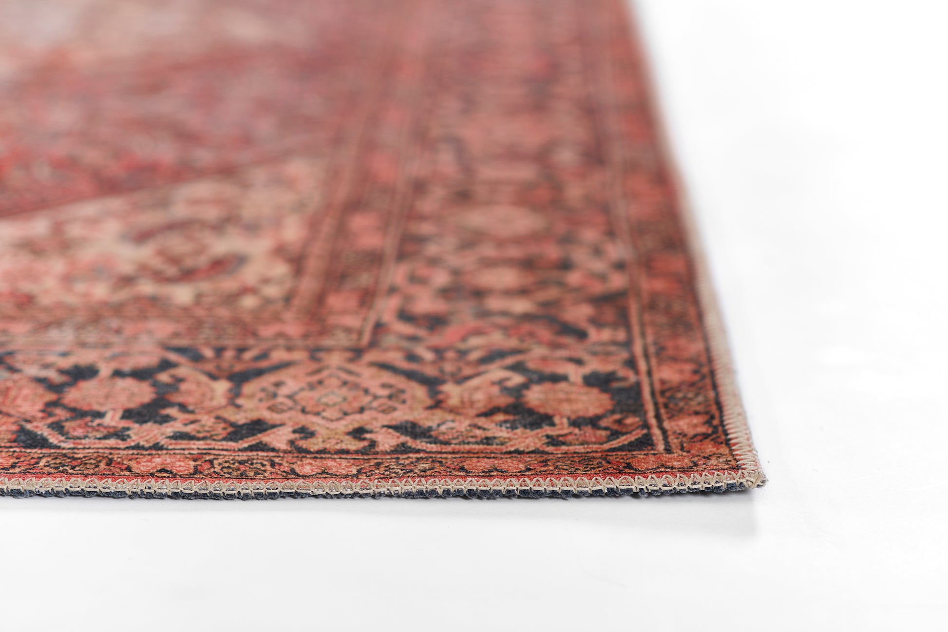 Red Persian-style rug edge close-up with dark blue and beige floral motifs; woven textile.