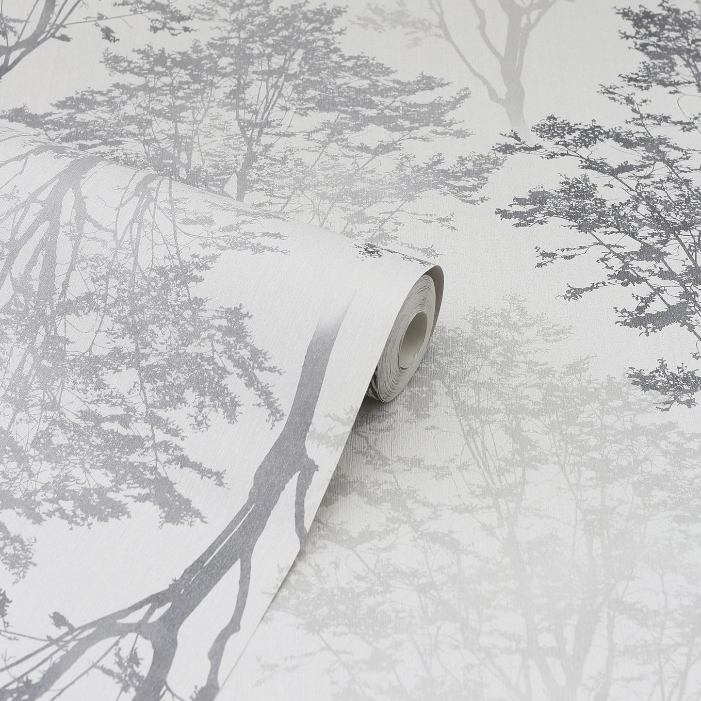 Gray-scale forest/tree branch wallpaper roll with rolled edge on a pale background; decorative wallcovering