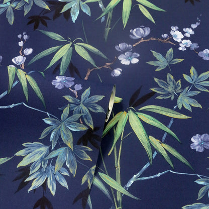 Navy blue fabric with bamboo leaves and pale purple flowers in green/teal tones; folded edge visible, botanical print.