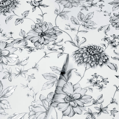 Monochrome floral wallpaper with hand-drawn petals and leaves; rolled corner reveals a repeating botanical pattern.