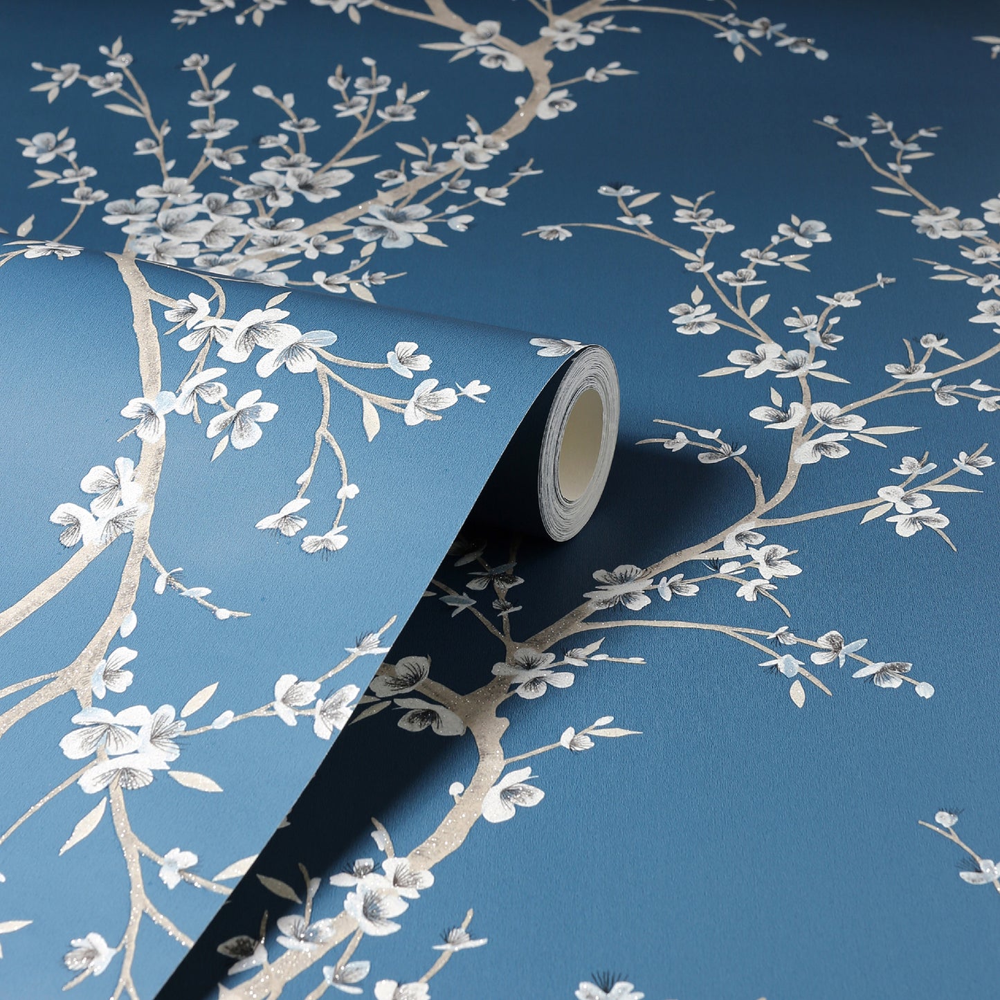 Blue wallpaper with white floral branches, rolled edge showing texture.