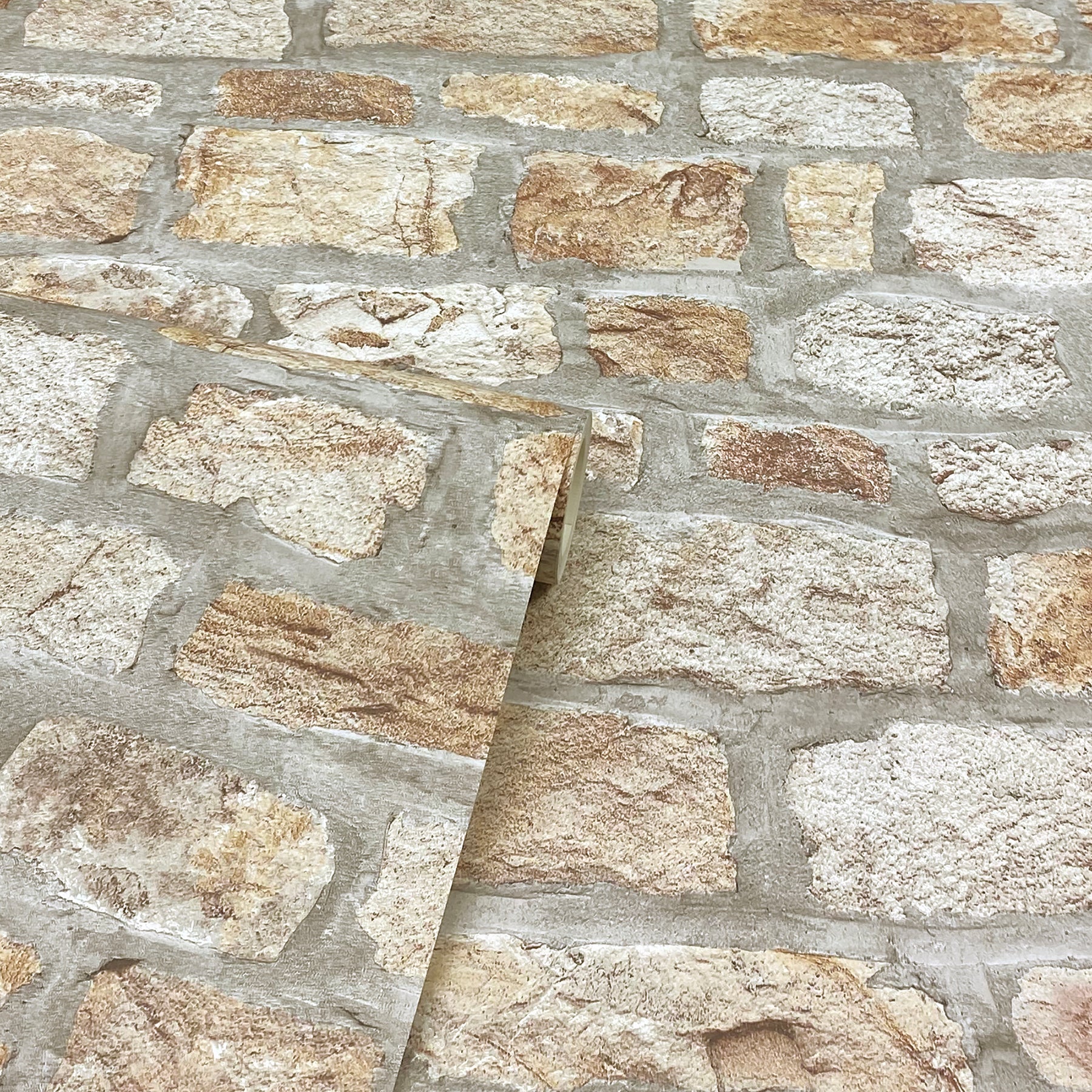 Close-up of beige & tan stone veneer wall with gray mortar; a diagonal sample panel rests on it.