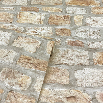 Close-up of beige & tan stone veneer wall with gray mortar; a diagonal sample panel rests on it.