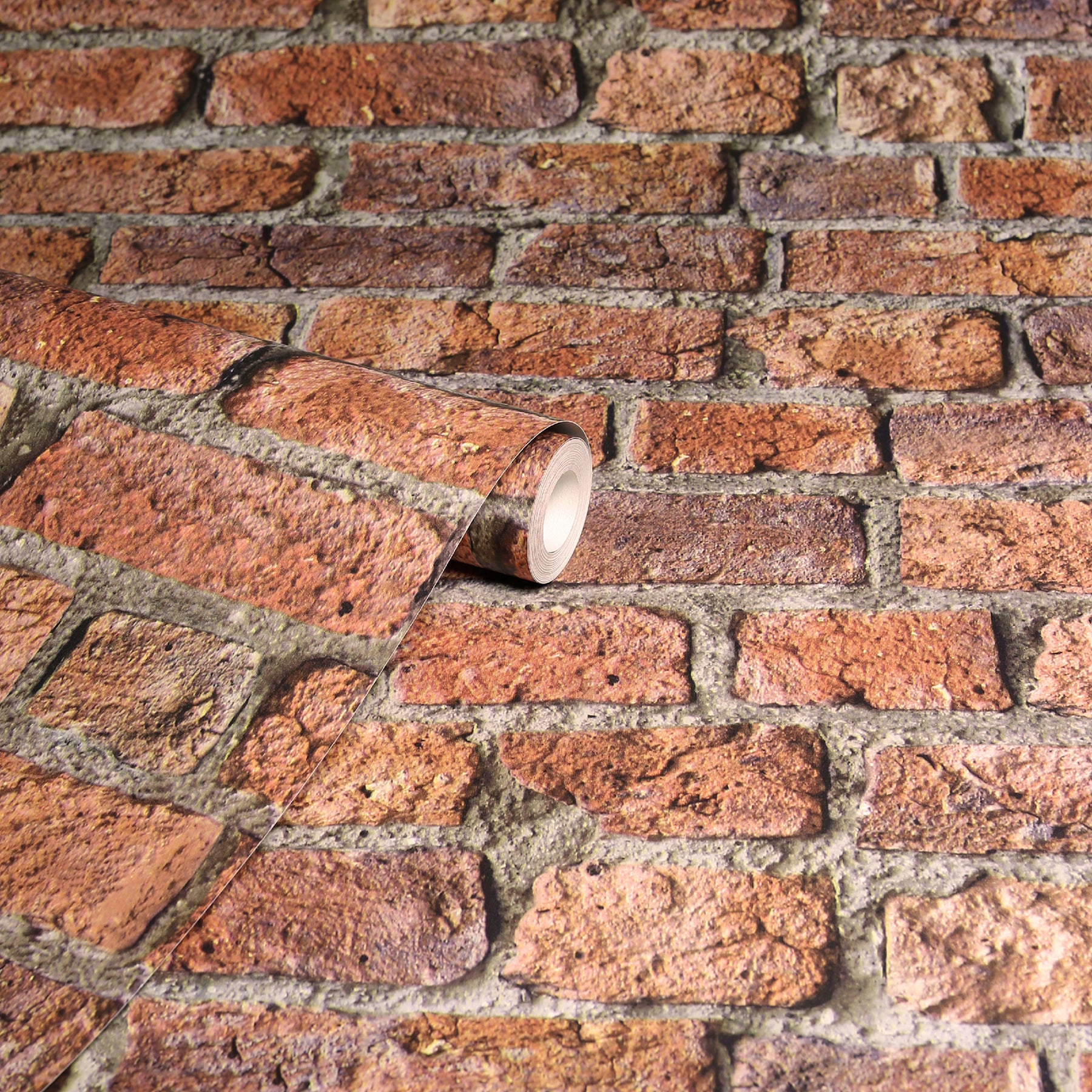 Rolled brick-pattern wallpaper sample with red-brown bricks and a white-core roll on a brick surface.