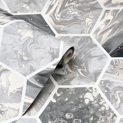 Grayscale marble hexagon wallpaper roll with white grout lines, curling from the roll.