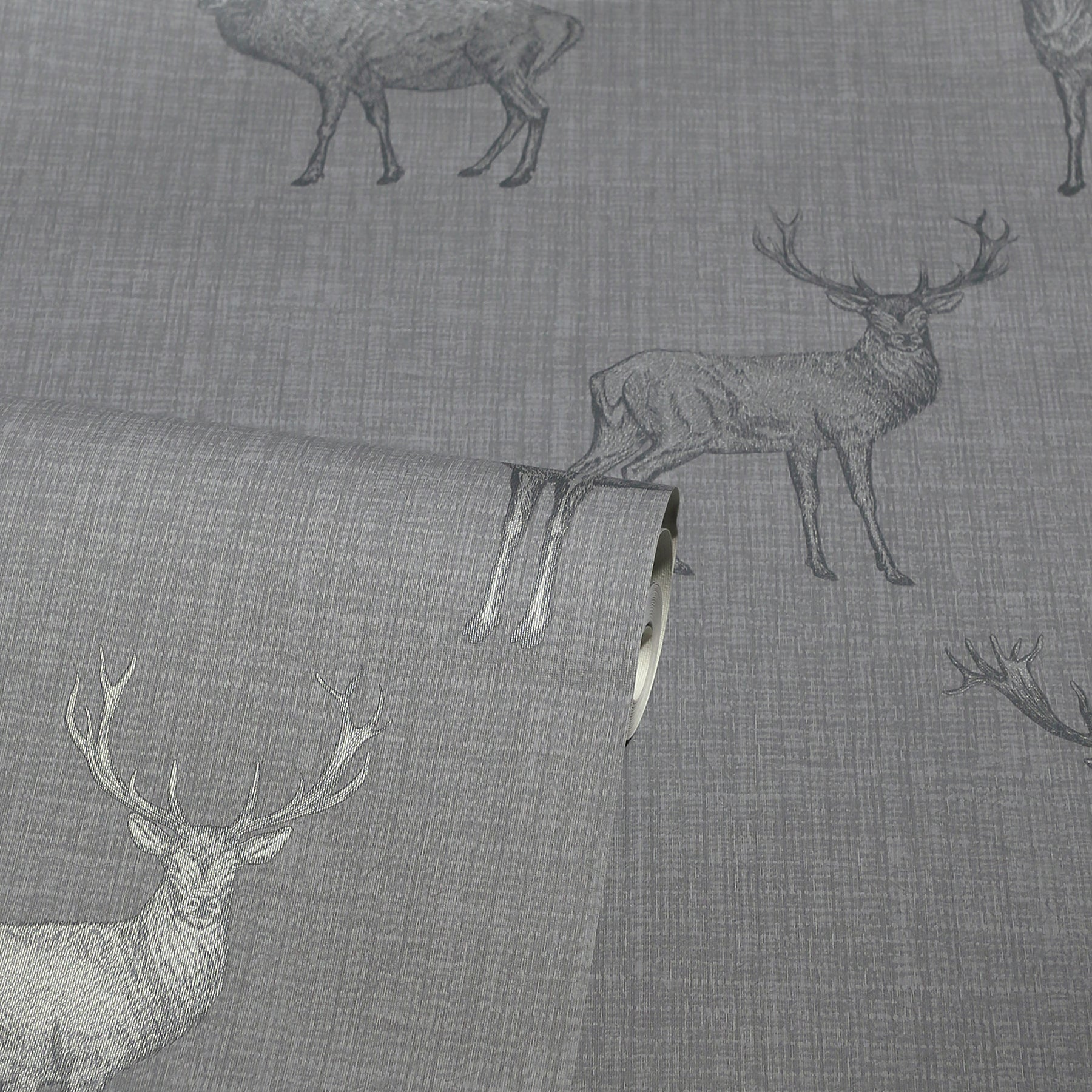 Gray linen-like fabric with deer silhouettes; rolled edge visible, rustic deer motif upholstery textile.