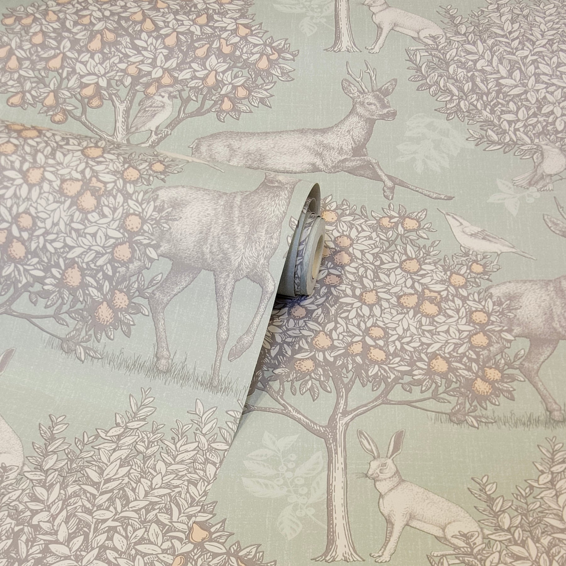 Sage green wallpaper in a vintage toile design with deer, rabbits and birds among blossoms; rolled edge visible.