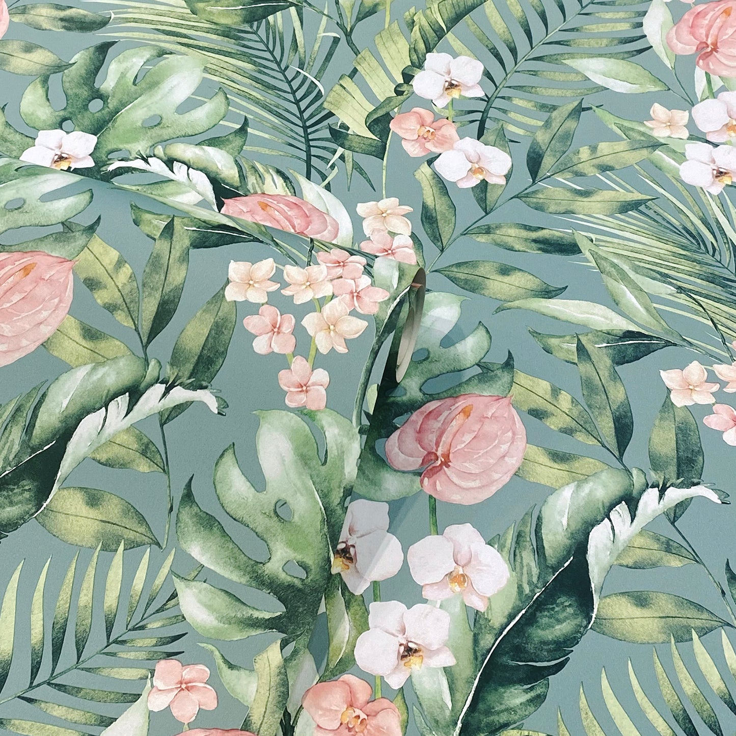 Tropical botanical print with green monstera and palm leaves and pink-white flowers on teal background.
