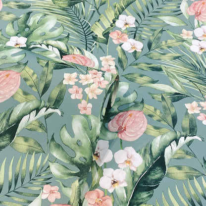 Tropical botanical print with green monstera and palm leaves and pink-white flowers on teal background.