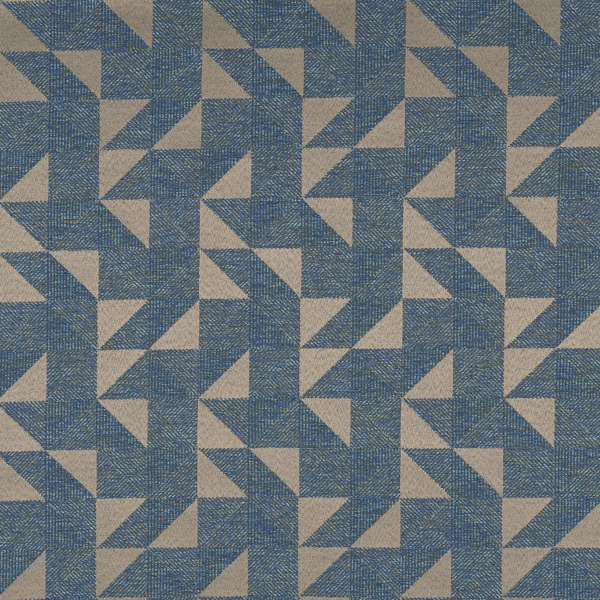 Blue, tan and green geometric triangles form a repeating pinwheel pattern on woven fabric.