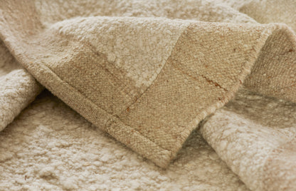 Beige plush terry towel or throw blanket with soft looped texture and subtle geometric pattern.