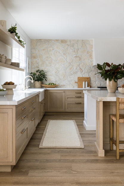Light-toned rug on the floor with nearby potted plants in an airy Scandinavian-style living space.