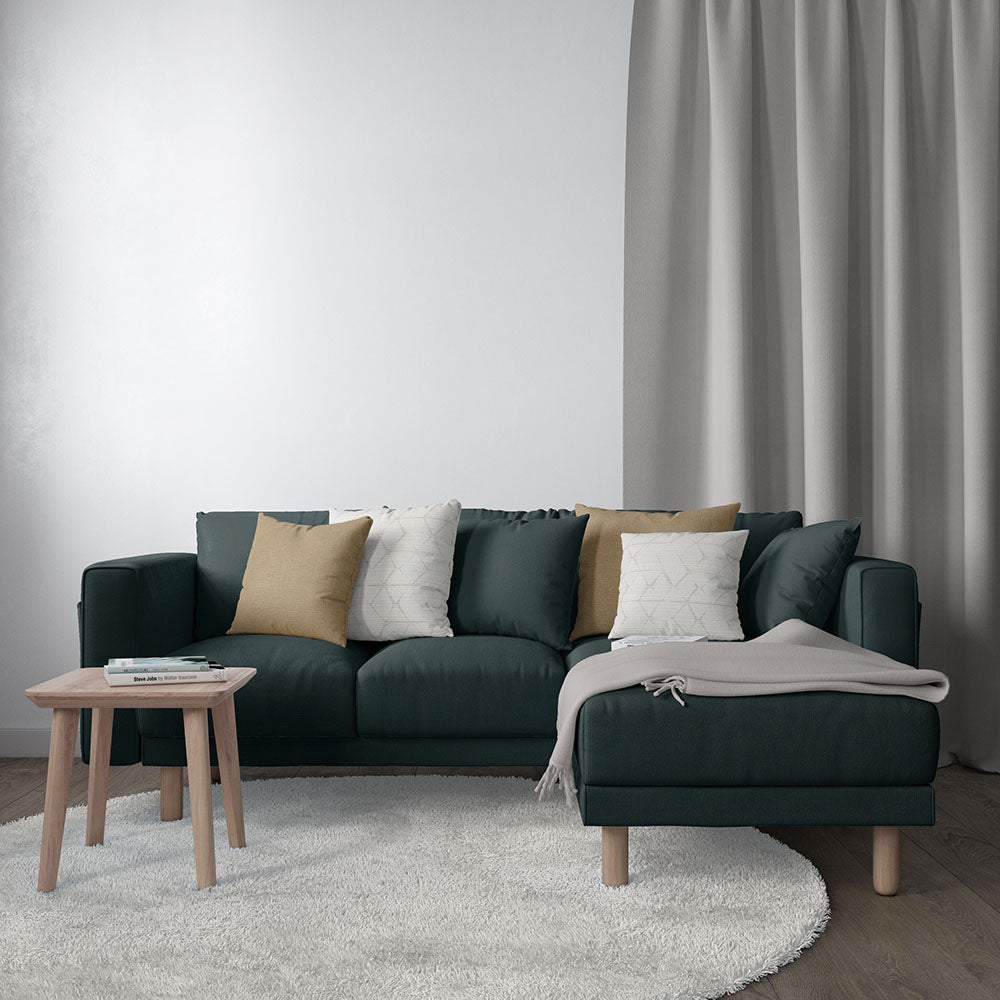 Moody blue solid velvet upholstery in a modern living room; dark blue sectional with chaise, mustard and white cushions, gray throw, wooden legs, side table.